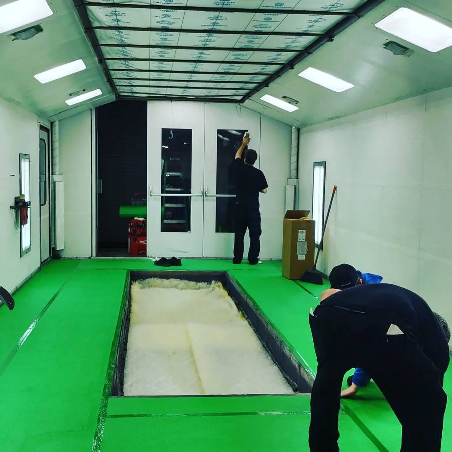 Crew laying new floor film around a booth pit